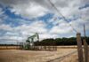 Oil edges down on easing Middle East risks but gains for a second month